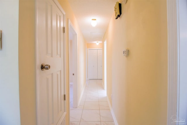 hall featuring baseboards and light tile patterned floors