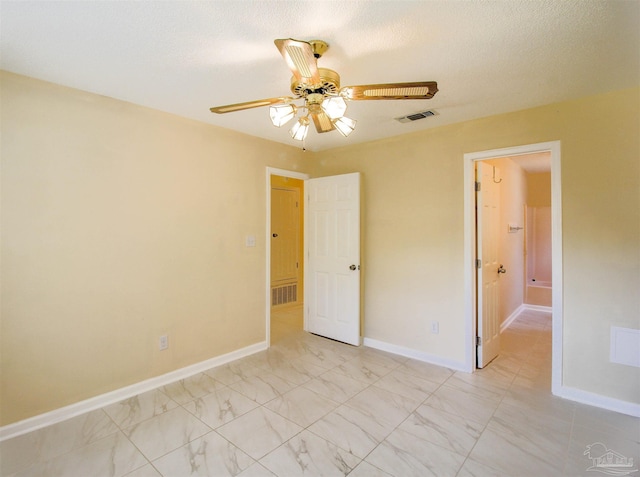 unfurnished bedroom with marble finish floor, baseboards, visible vents, and a textured ceiling