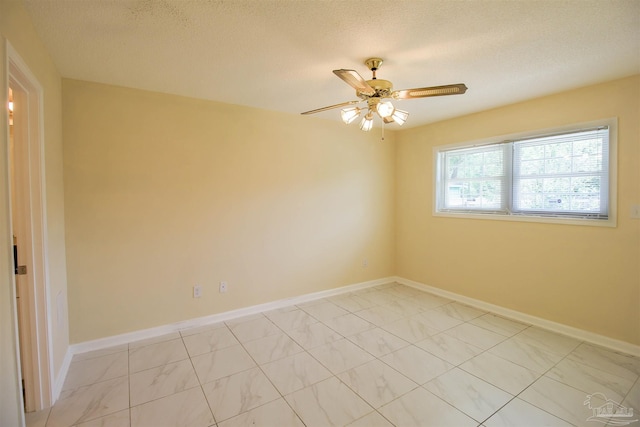 empty room with a textured ceiling, ceiling fan, and baseboards