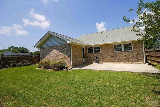 back of house with brick siding, a yard, fence, and a patio