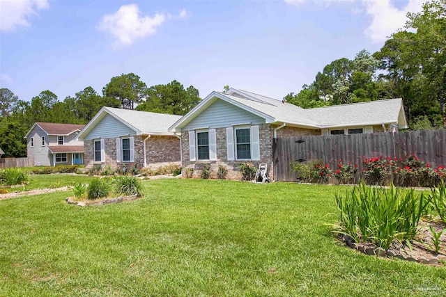 ranch-style home featuring fence, a front lawn, and brick siding