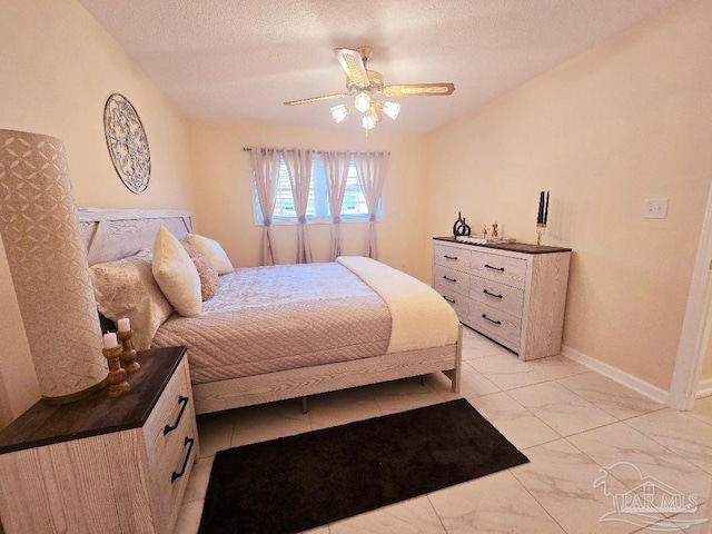 bedroom featuring a ceiling fan, marble finish floor, a textured ceiling, and baseboards