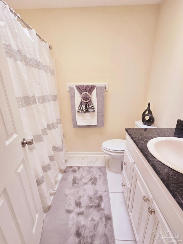 bathroom featuring toilet, baseboards, a shower with shower curtain, and vanity