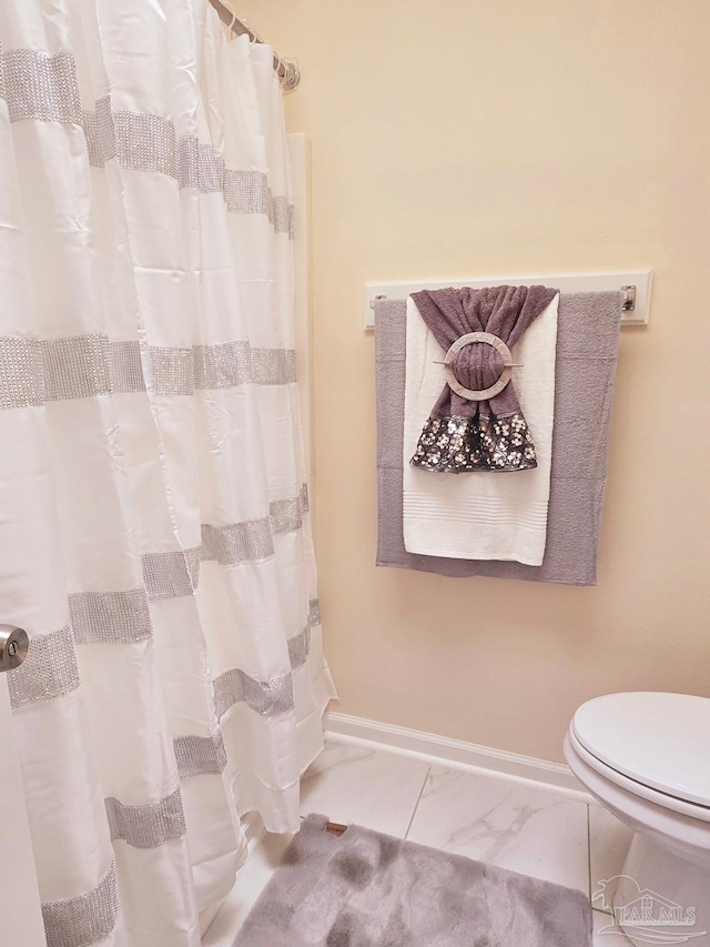 full bath with toilet, marble finish floor, a shower with curtain, and baseboards