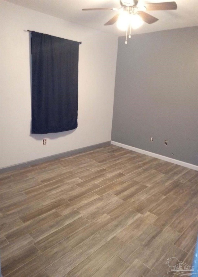 unfurnished room with ceiling fan, wood finished floors, and baseboards