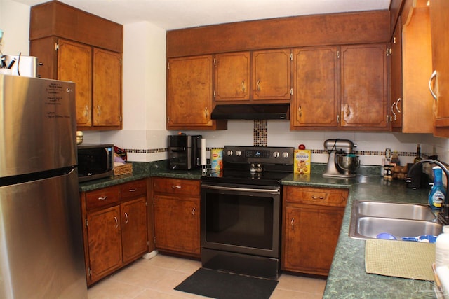 kitchen featuring stainless steel appliances, dark countertops, a sink, and under cabinet range hood