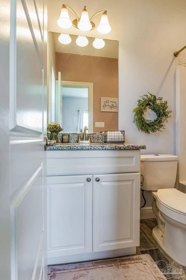 bathroom with wood-type flooring, toilet, and vanity