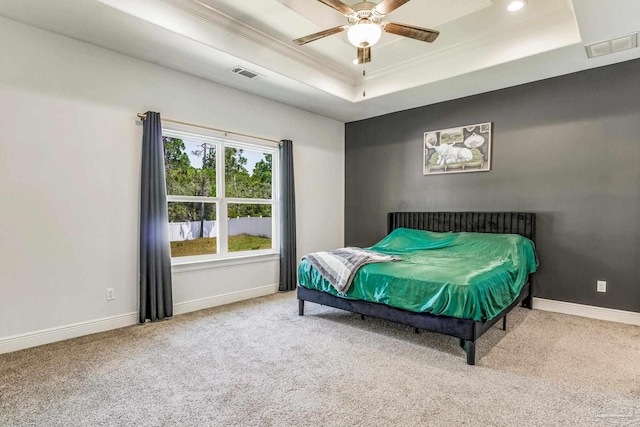 carpeted bedroom with ceiling fan and a tray ceiling