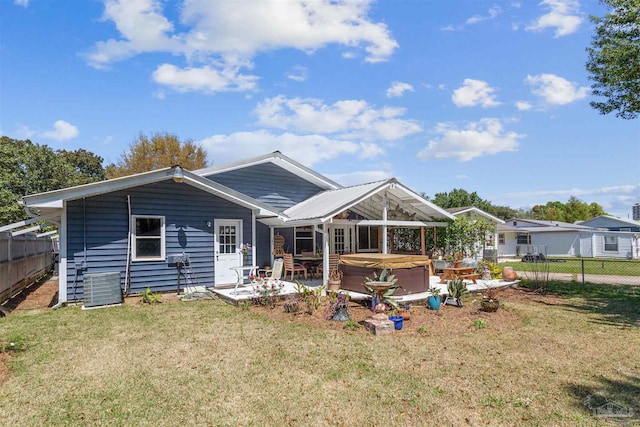 back of property featuring a yard, a patio area, and a hot tub