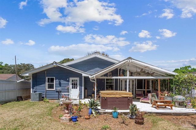 rear view of property with a yard, a hot tub, and a patio