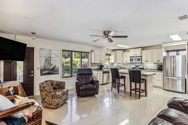 living room featuring light tile patterned floors, a textured ceiling, and ceiling fan