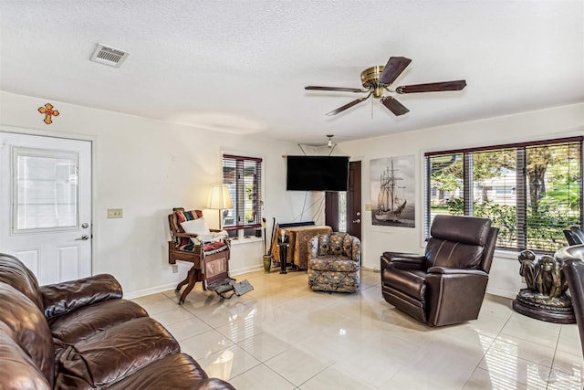 tiled living room with ceiling fan and a textured ceiling