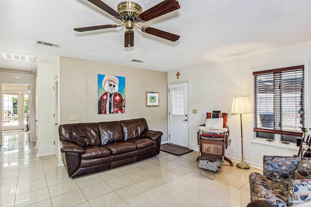 living room featuring ceiling fan, a textured ceiling, and light tile patterned floors