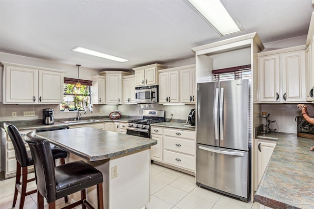 kitchen featuring sink, hanging light fixtures, a kitchen island, stainless steel appliances, and a kitchen bar