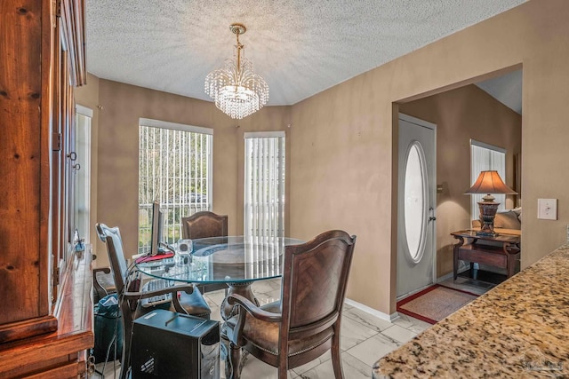 dining space featuring an inviting chandelier and a textured ceiling