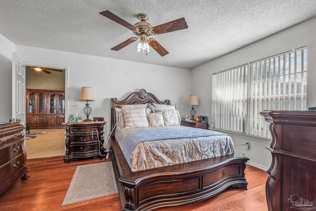 bedroom with ceiling fan, hardwood / wood-style floors, and a textured ceiling