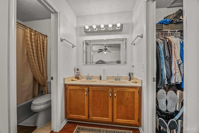 full bathroom featuring shower / bathtub combination with curtain, toilet, vanity, ceiling fan, and a textured ceiling