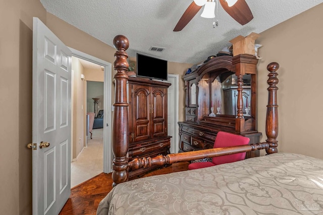 bedroom with ceiling fan, dark hardwood / wood-style flooring, and a textured ceiling