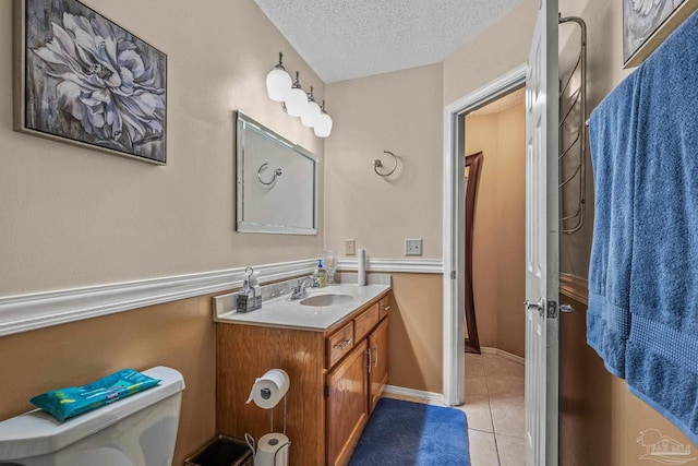 bathroom featuring vanity, toilet, tile patterned flooring, and a textured ceiling