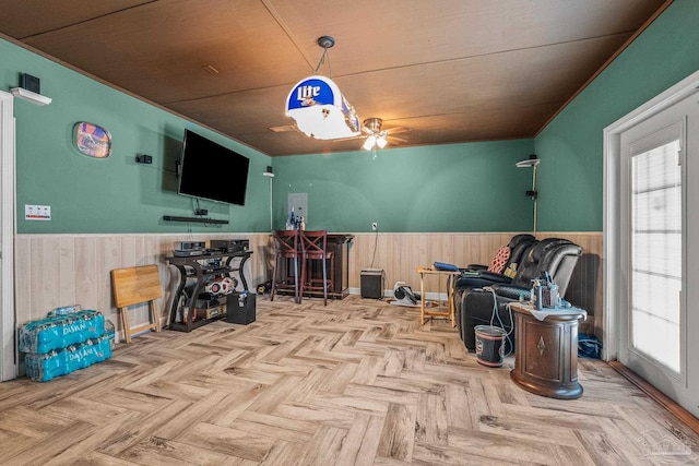 sitting room featuring wooden ceiling, wood walls, ceiling fan, and light parquet floors