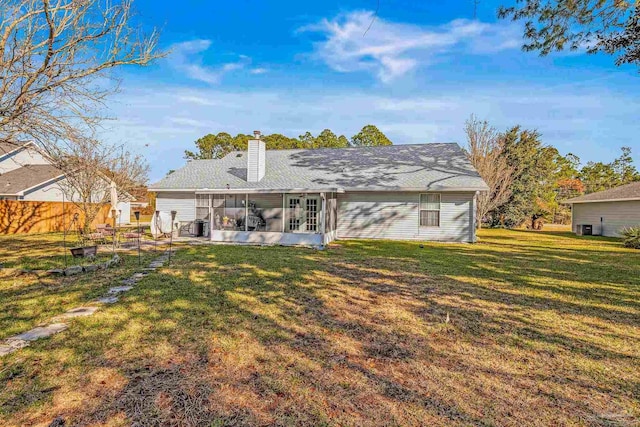 rear view of house featuring a lawn and a sunroom