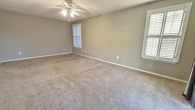 empty room featuring ceiling fan, a textured ceiling, light carpet, and baseboards