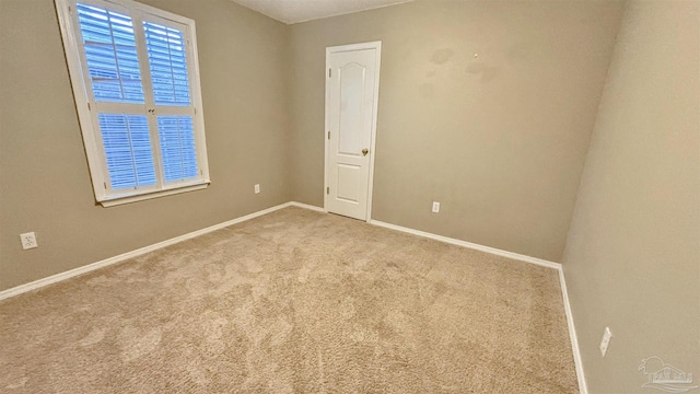 unfurnished room with light carpet and baseboards