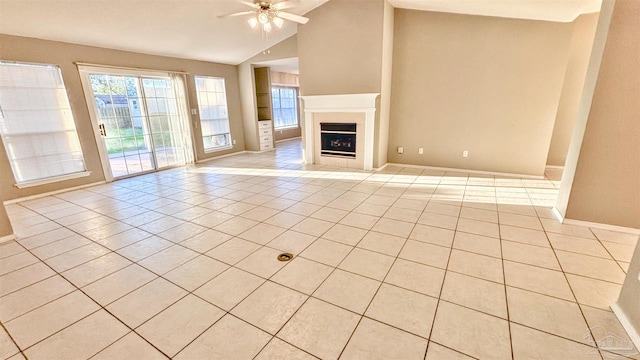 unfurnished living room with a fireplace, light tile patterned floors, lofted ceiling, ceiling fan, and baseboards