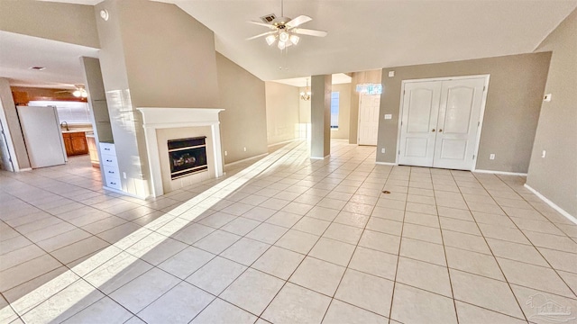 unfurnished living room featuring high vaulted ceiling, ceiling fan with notable chandelier, a fireplace, and light tile patterned floors