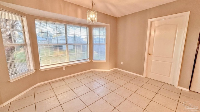 unfurnished room with light tile patterned floors, baseboards, and a chandelier