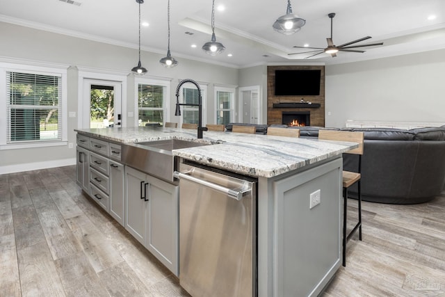 kitchen with light stone countertops, an island with sink, light hardwood / wood-style flooring, and stainless steel dishwasher