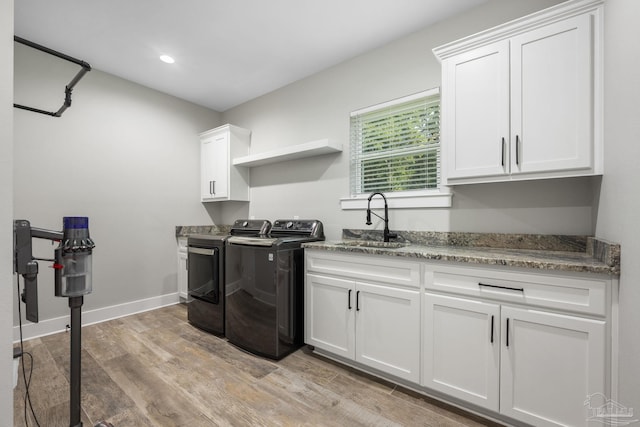 washroom with cabinets, separate washer and dryer, light wood-type flooring, and sink