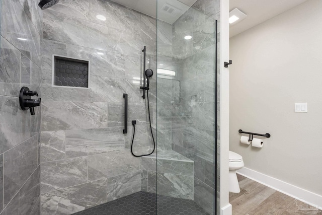 bathroom featuring hardwood / wood-style floors, a shower with door, and toilet