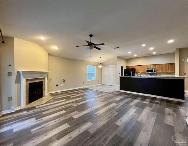 unfurnished living room featuring ceiling fan, dark wood-type flooring, vaulted ceiling, and sink