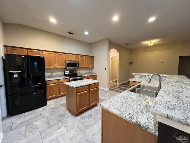 kitchen featuring sink, a center island with sink, light stone counters, and appliances with stainless steel finishes