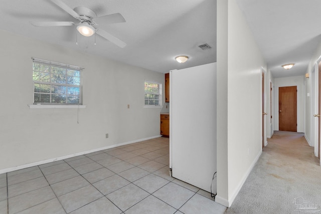 spare room featuring a wealth of natural light, ceiling fan, and light tile patterned floors