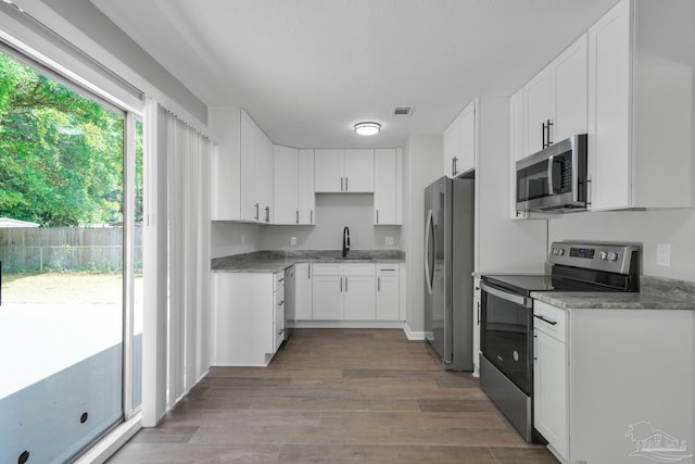 5686 Avondale Rd, Pensacola, FL 32526 - kitchen featuring white cabinetry, wood finished floors, appliances with stainless steel finishes, and a sink