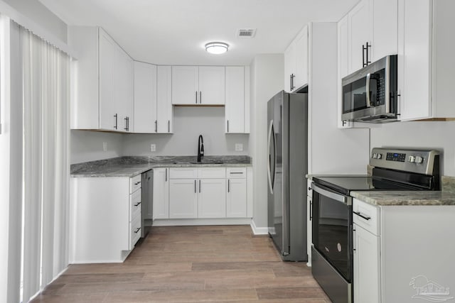 5686 Avondale Rd, Pensacola, FL 32526 - kitchen with light stone counters, visible vents, a sink, appliances with stainless steel finishes, and light wood-type flooring