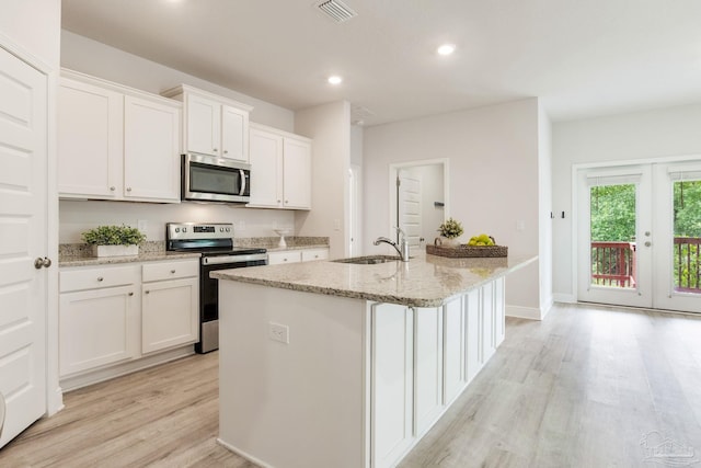 7822 Burnside Loop, Pensacola, FL 32526 - kitchen with stainless steel appliances, light wood-style flooring, white cabinetry, an island with sink, and light stone counters