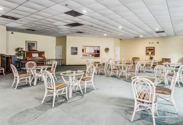 dining area featuring carpet floors and a drop ceiling