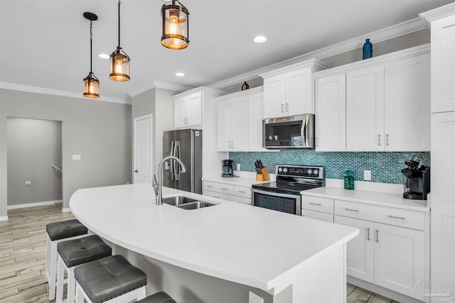 kitchen featuring appliances with stainless steel finishes, an island with sink, decorative light fixtures, and sink