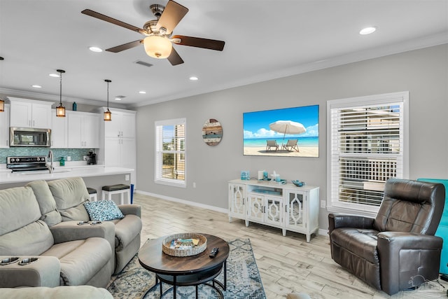 living room with ceiling fan, crown molding, and light hardwood / wood-style flooring