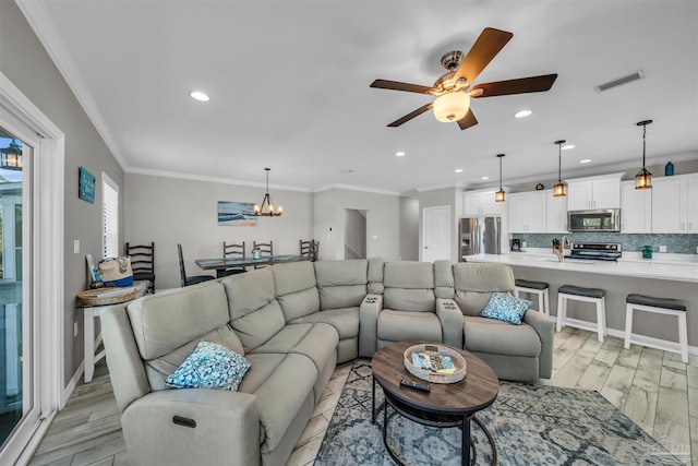 living room featuring ceiling fan with notable chandelier, light hardwood / wood-style floors, and crown molding