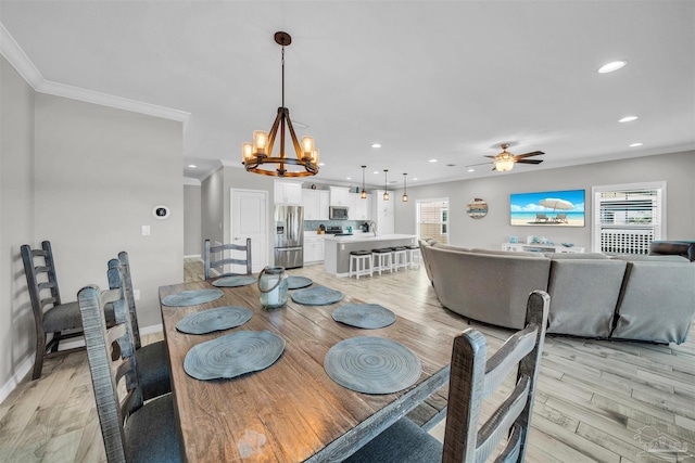 dining space featuring ceiling fan with notable chandelier, light hardwood / wood-style floors, ornamental molding, and sink