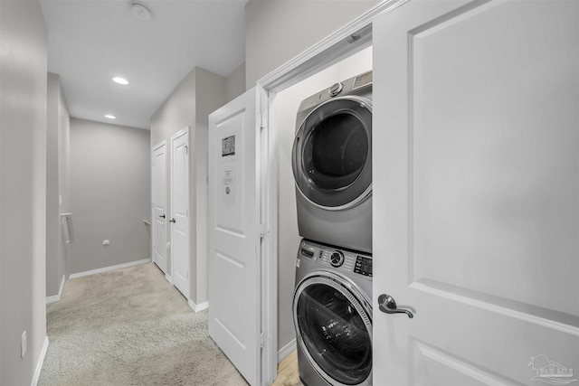 clothes washing area with stacked washing maching and dryer and light carpet