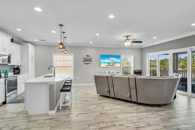 interior space with ceiling fan, sink, ornamental molding, and light wood-type flooring