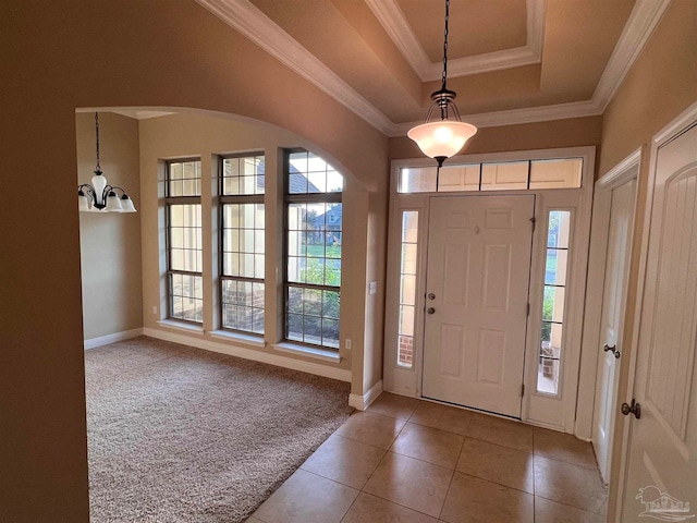 foyer with a raised ceiling, crown molding, and light tile patterned floors