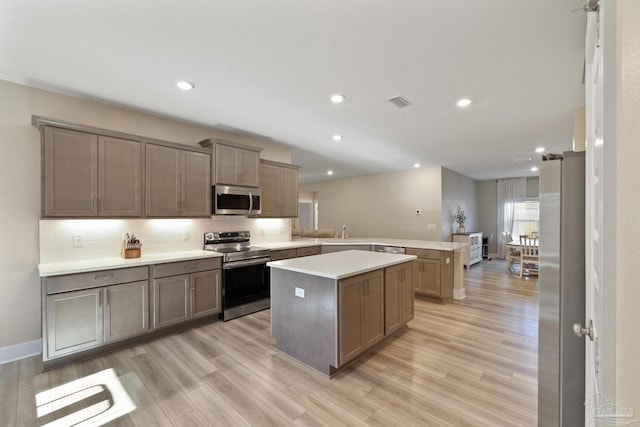 kitchen featuring a center island, sink, light hardwood / wood-style flooring, appliances with stainless steel finishes, and kitchen peninsula