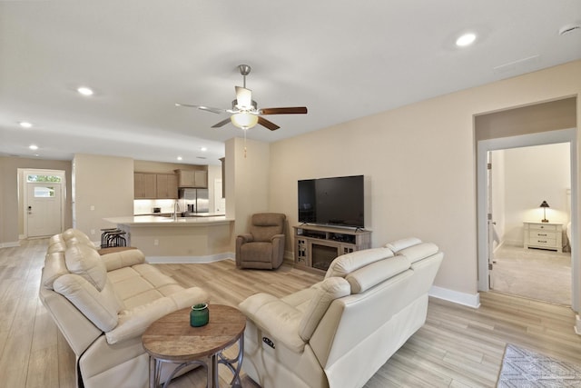 living room featuring ceiling fan, sink, and light hardwood / wood-style floors