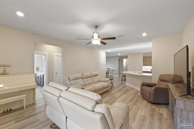 living room featuring light hardwood / wood-style floors, ceiling fan, and sink